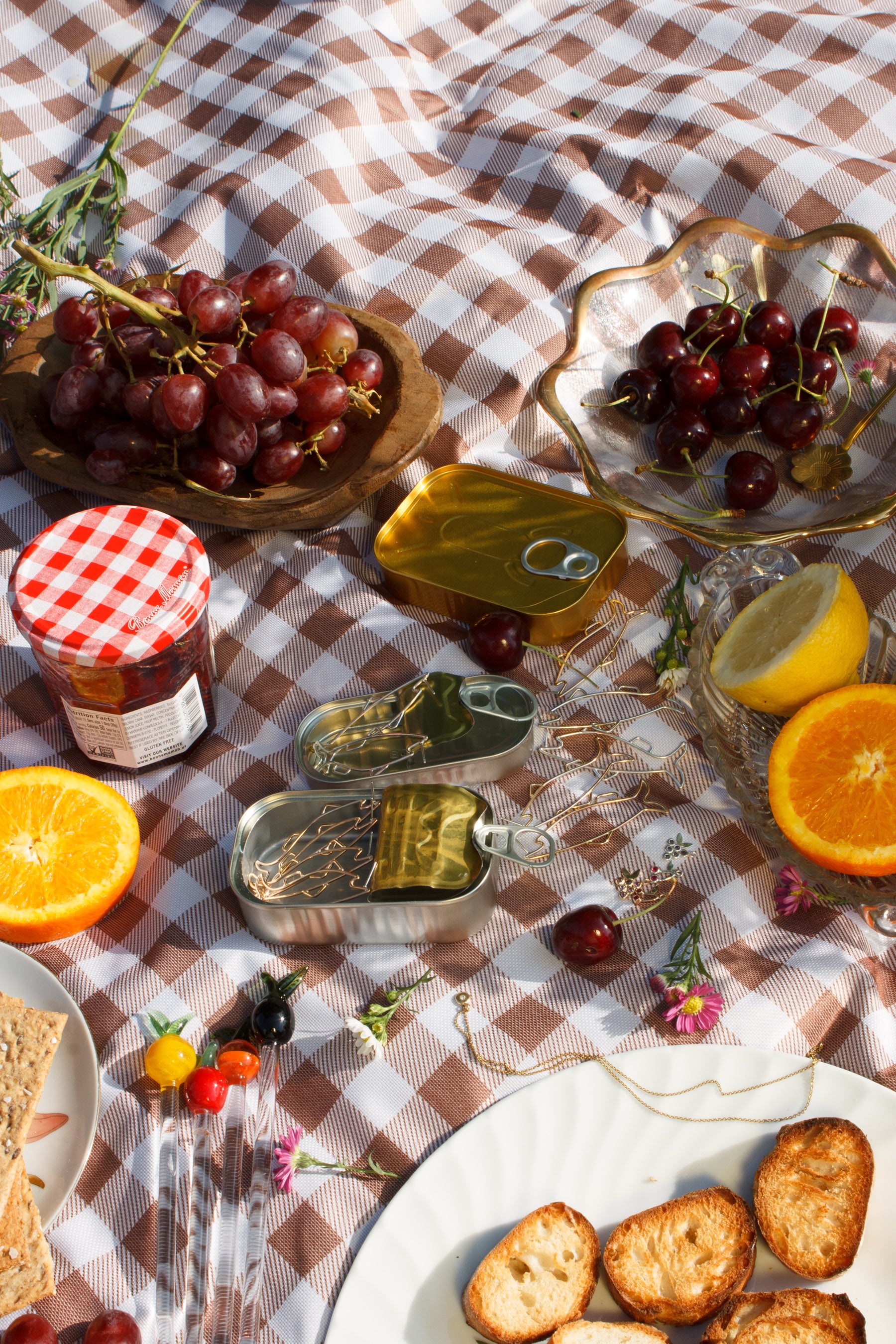 Outdoor picnic setup with fruits, bread, and a checkered tablecloth